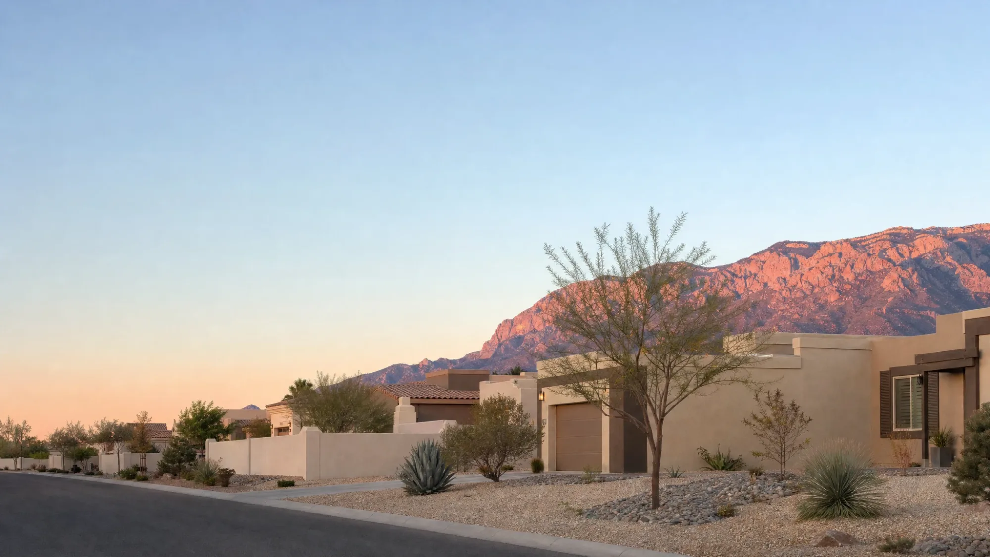 Freshly painted stucco homes on a Northeast Heights street with the Sandia Mountains behind them