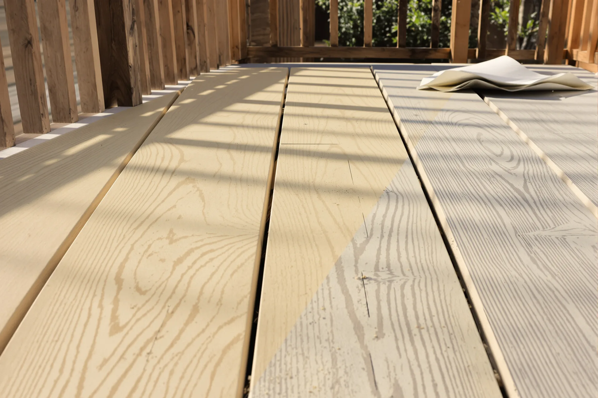 Deck boards sanded back to clean pale wood next to boards still weathered gray