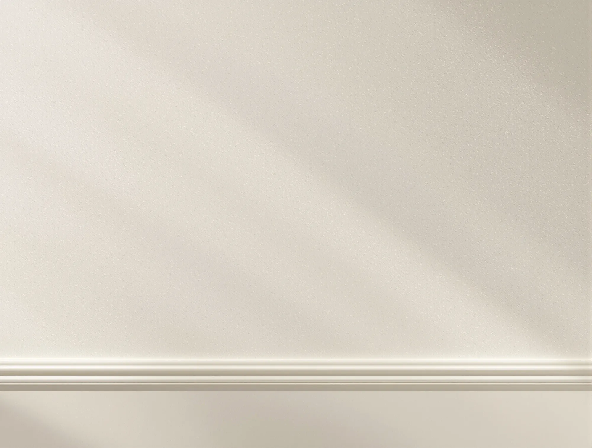 Smooth, flat warm white wall in soft afternoon light above a white baseboard