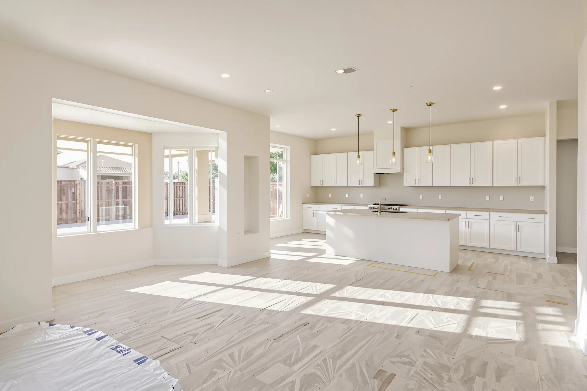 Newly built open living and kitchen area with smooth warm white walls and new white cabinets