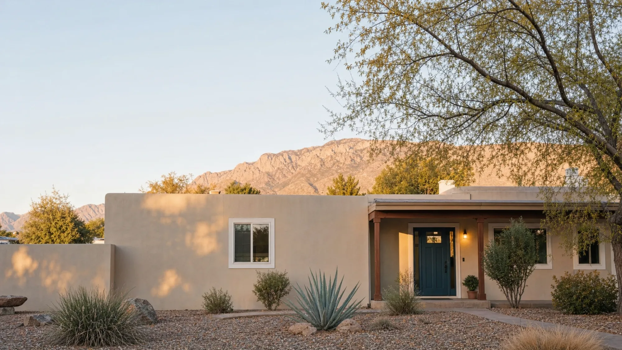 Freshly painted single-story stucco home with white trim and a blue-green front door